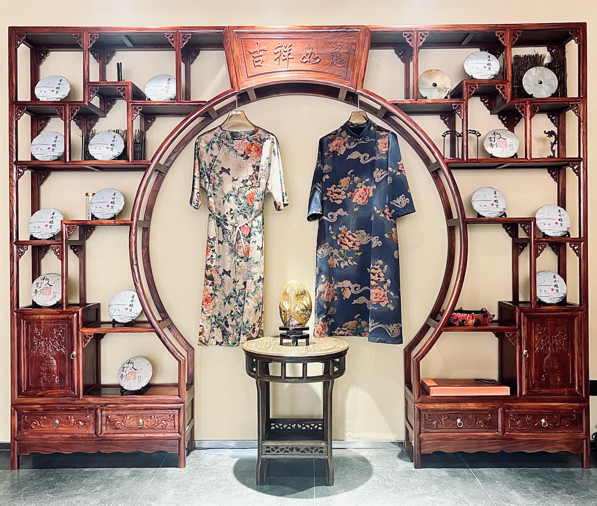 Two digital Chinese-style garments hanging in the centre of a Chinese-style cabinet.