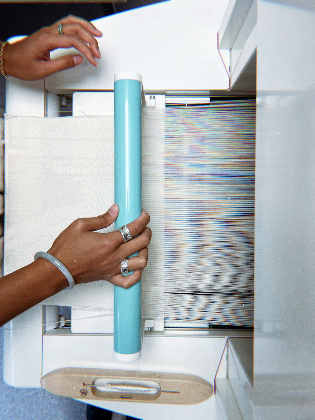 Person holding blue part of a loom, white.