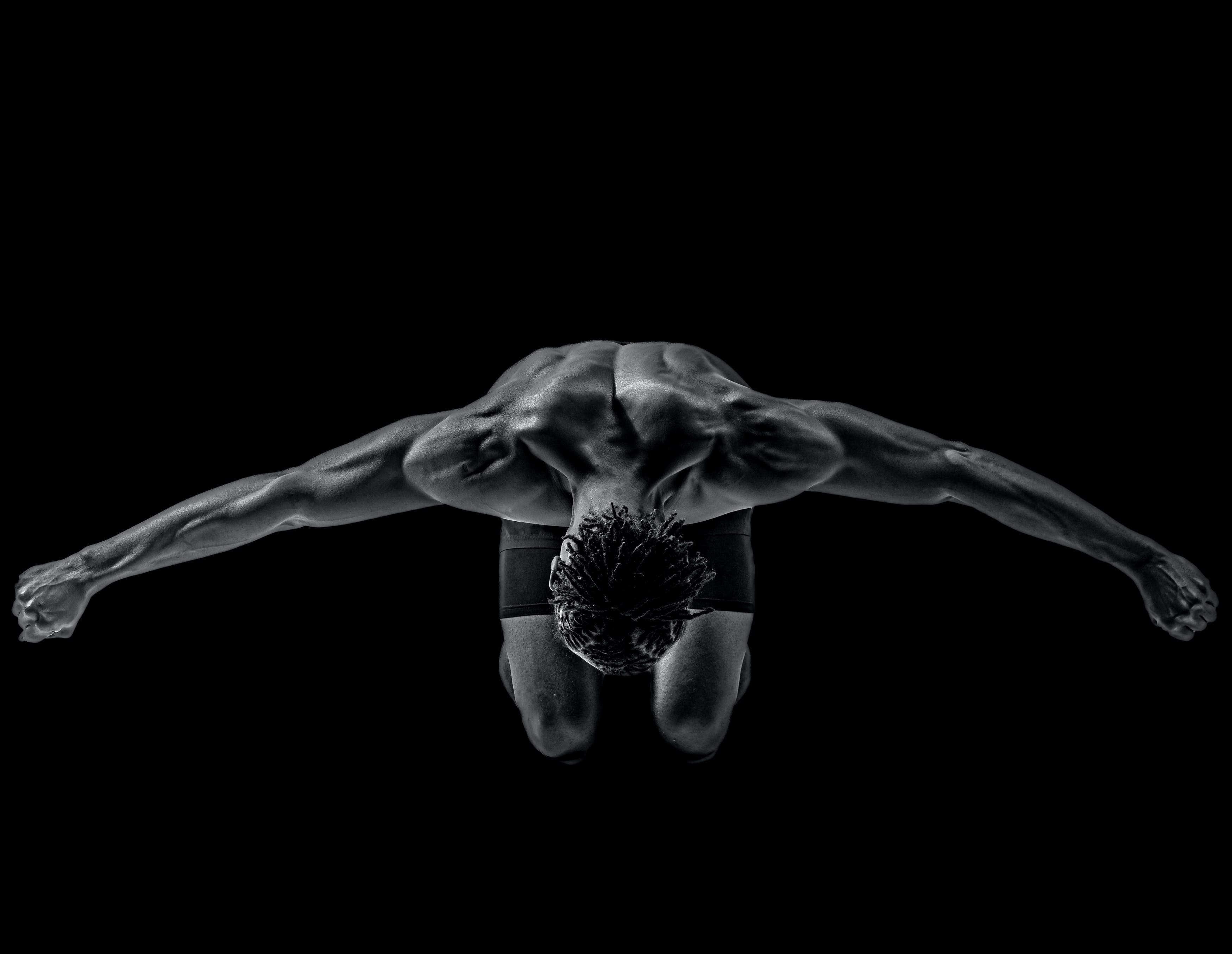 Aerial view of a shirtless muscular man with their arms outstretched.