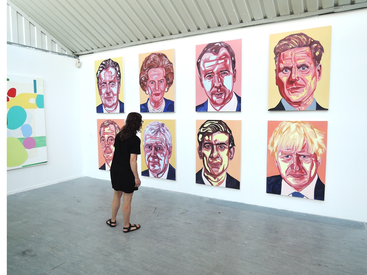A person stood in front of a collection of paintings of British Prime Ministers.