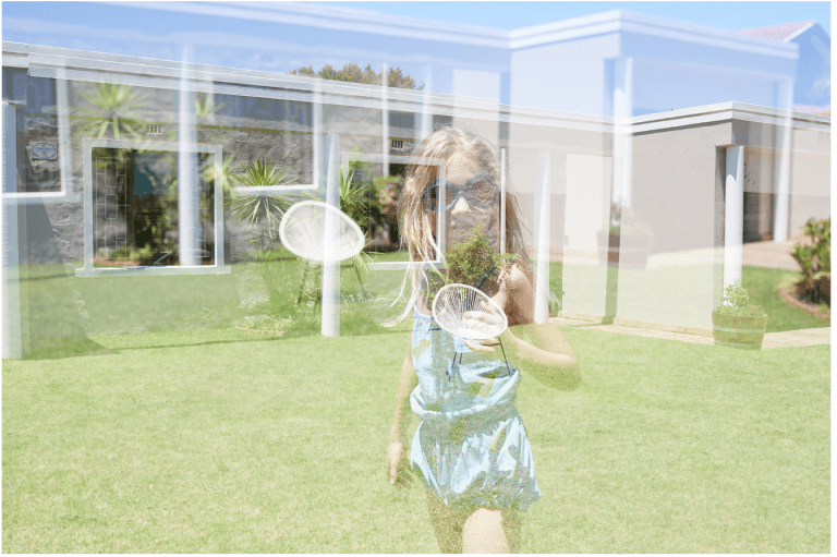Translucent image or reflection of a child in a swimming costume in a garden.