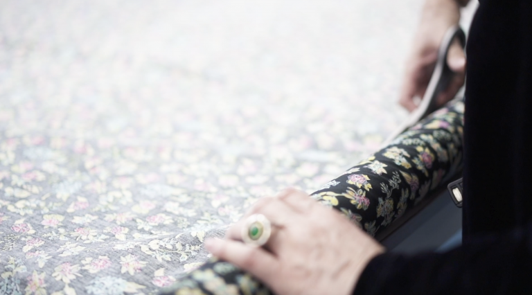 A person cuts a roll of fabric with a pair of scissors.