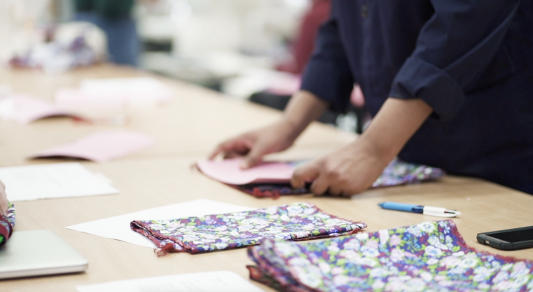 Folds of fabric lying on a table with a person working in the background.