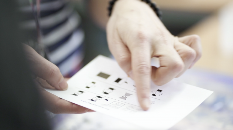 A person holding a piece of paper and pointing at a detail.