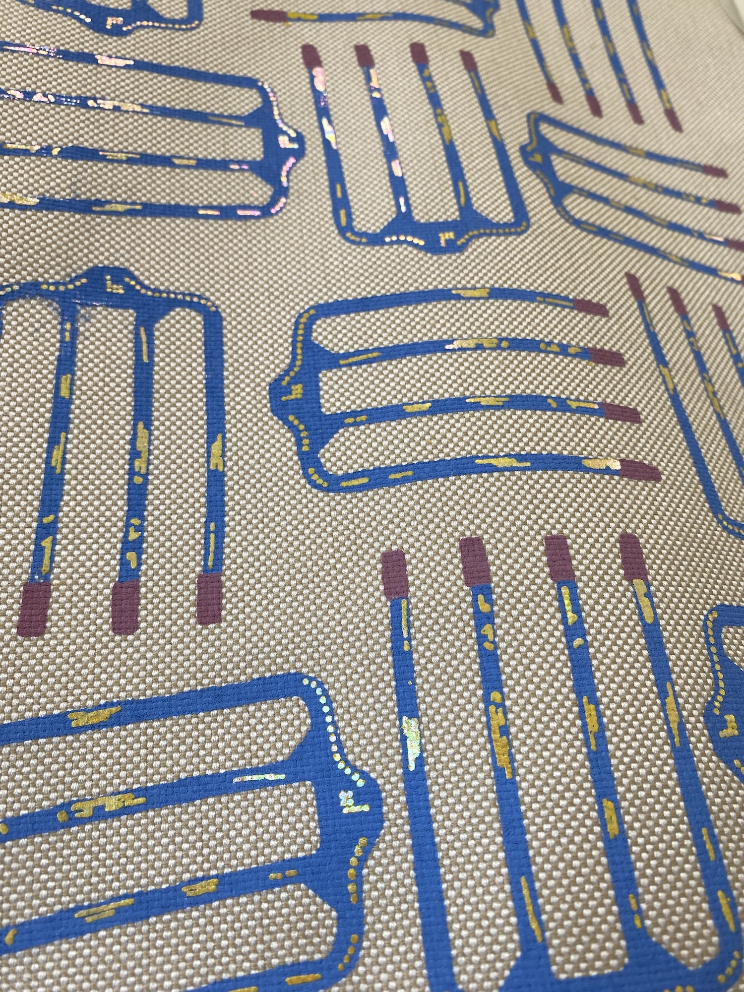 A close-up of a beige patterned fabric with blue and purple outlined abstract shapes.