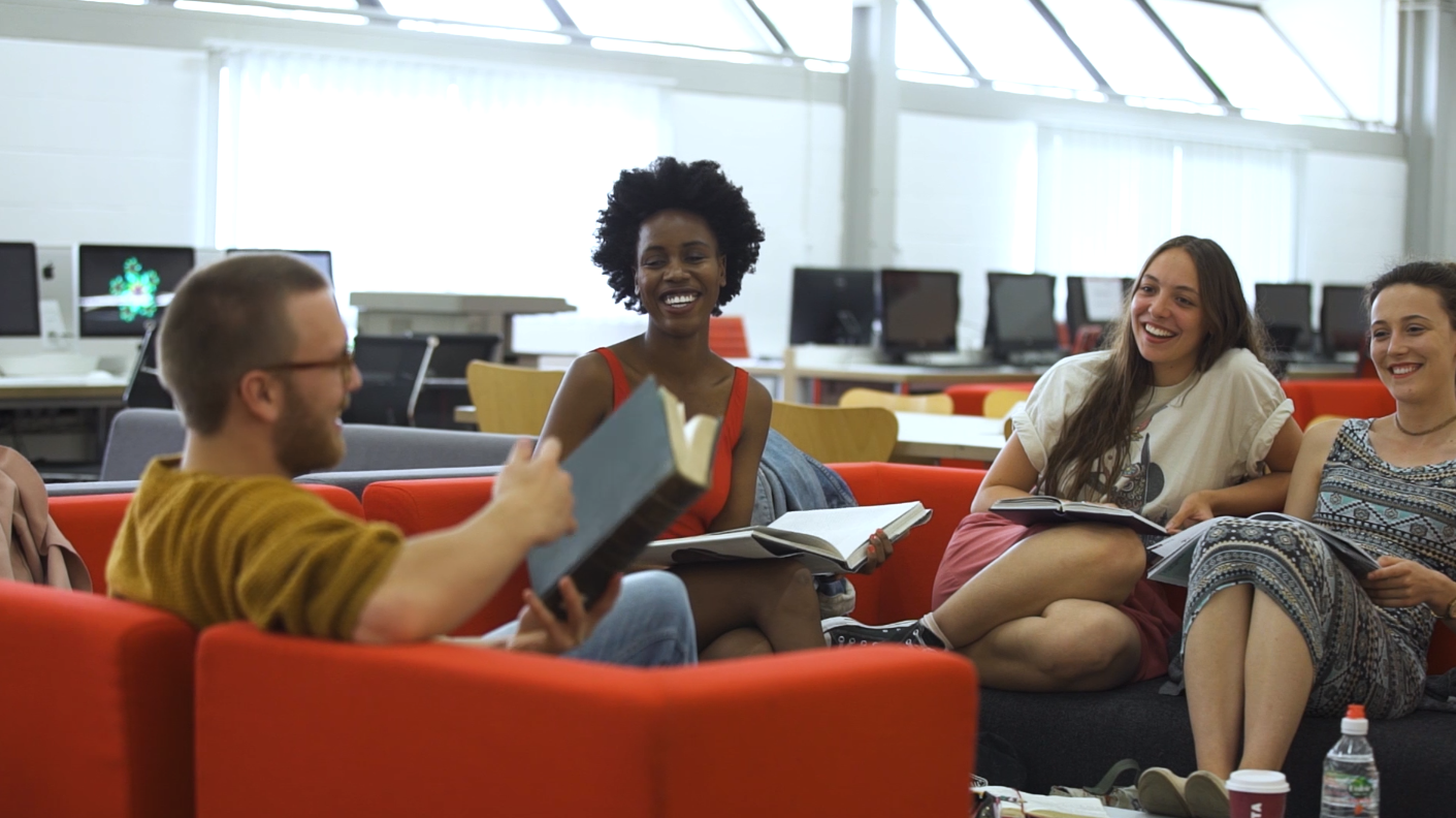 Students sitting in the library and discussing a book