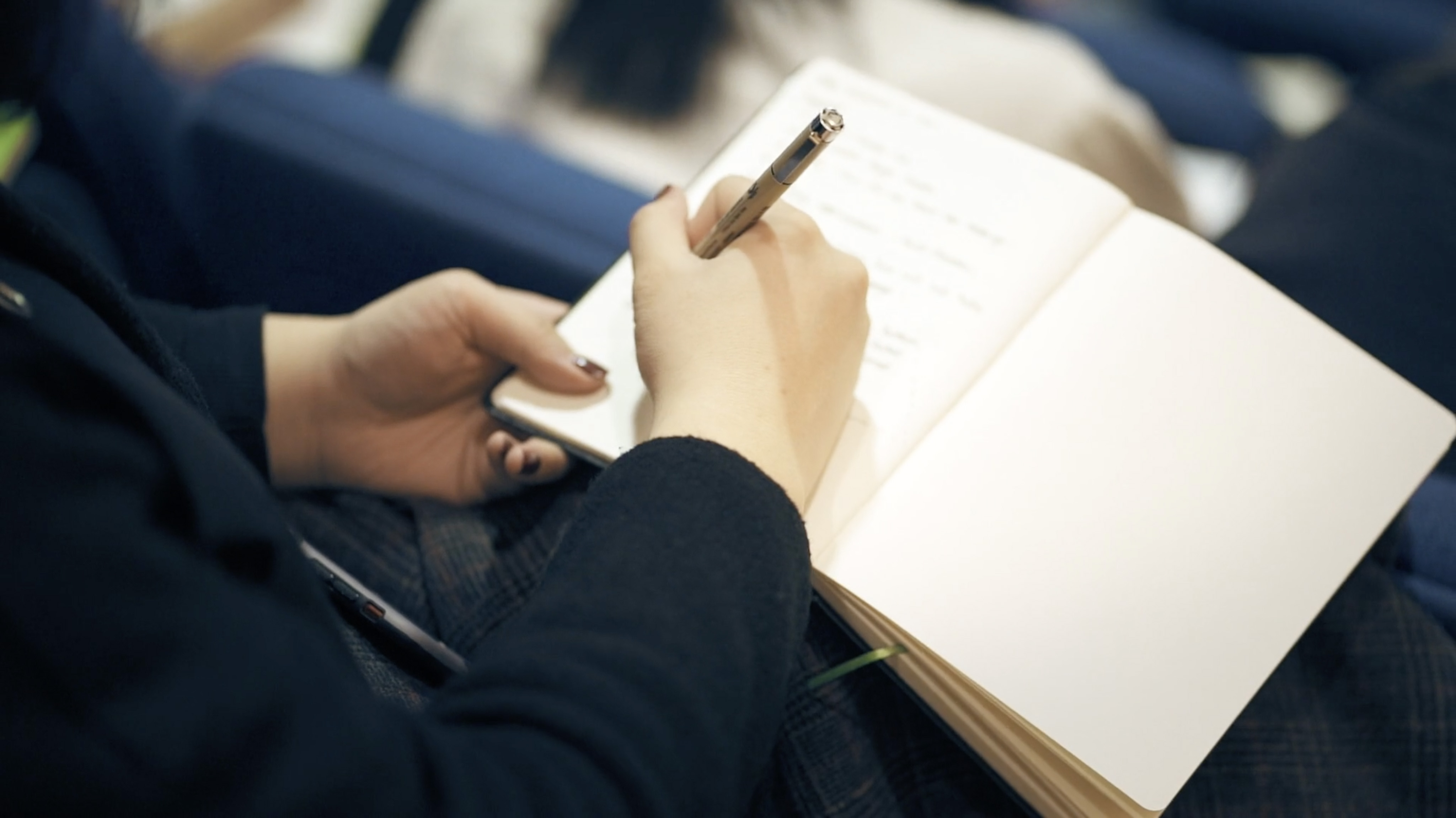 A person writes in a notebook on their lap.