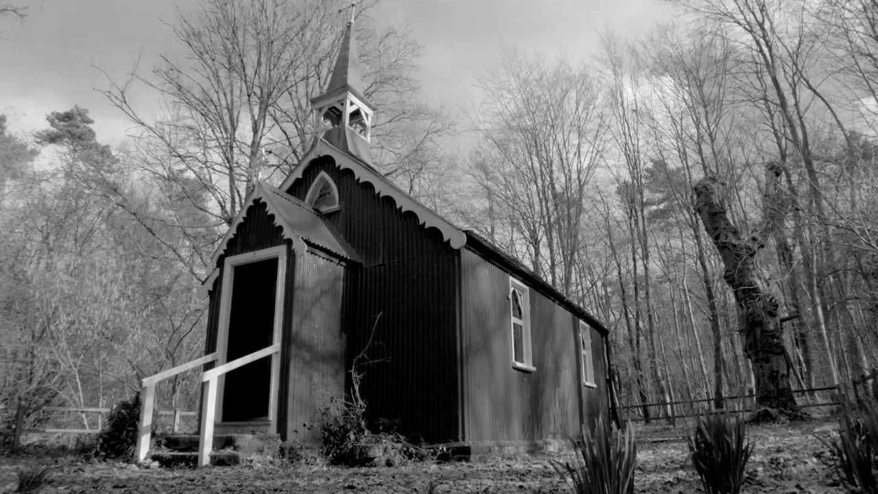 Black and white image of a traditional church in a forest.
