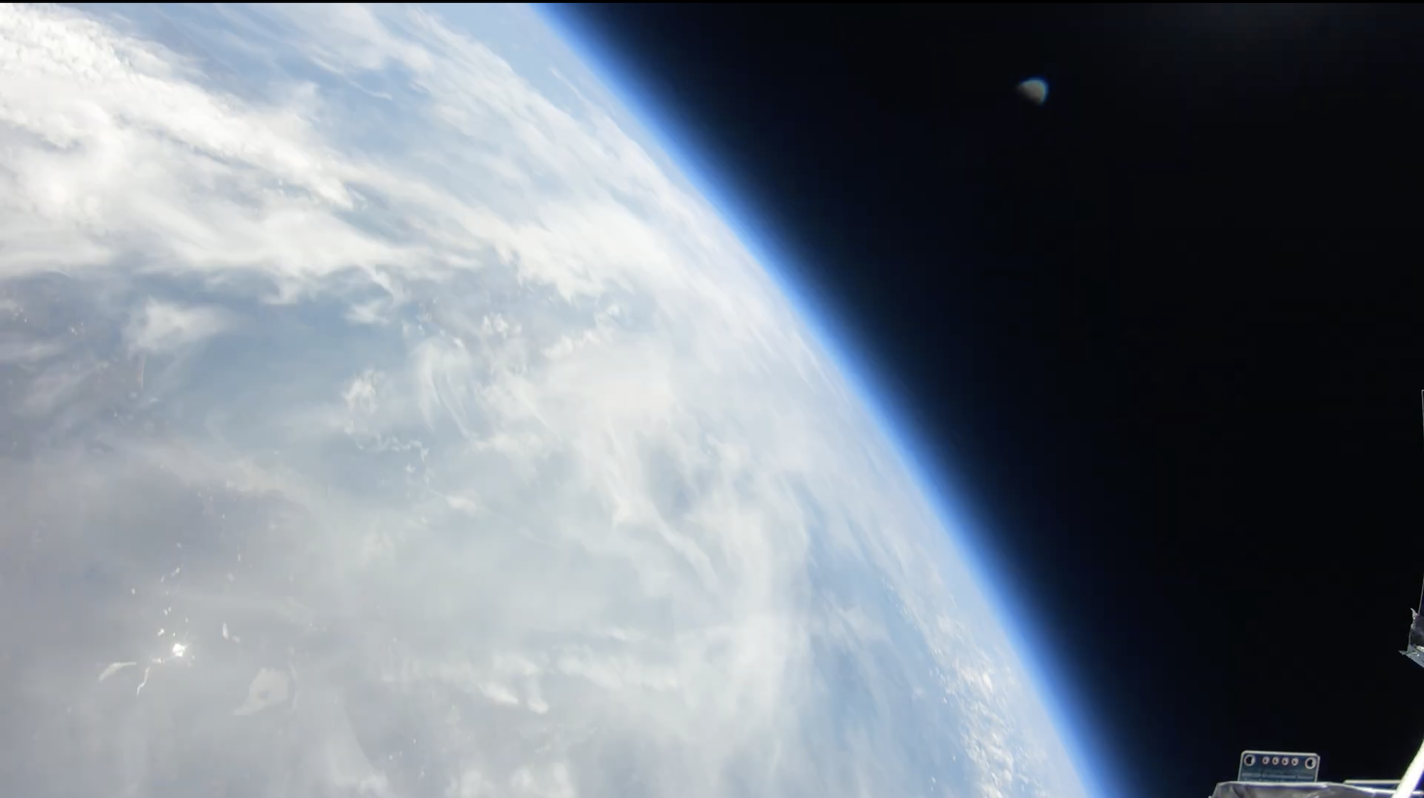 Earth's curved surface with blue and white swirled patterns against black space, bright blue atmospheric edge visible.