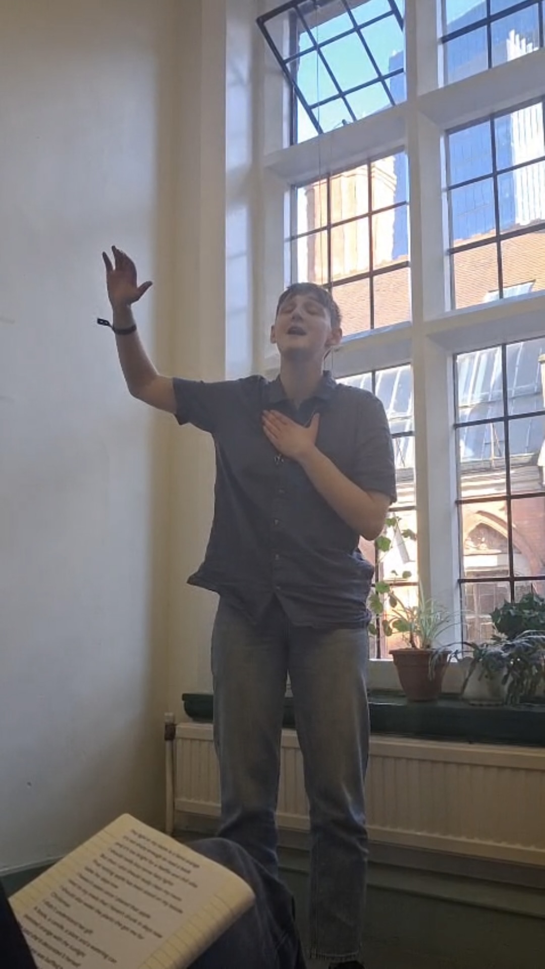 Person performing spoken word in front of large window.