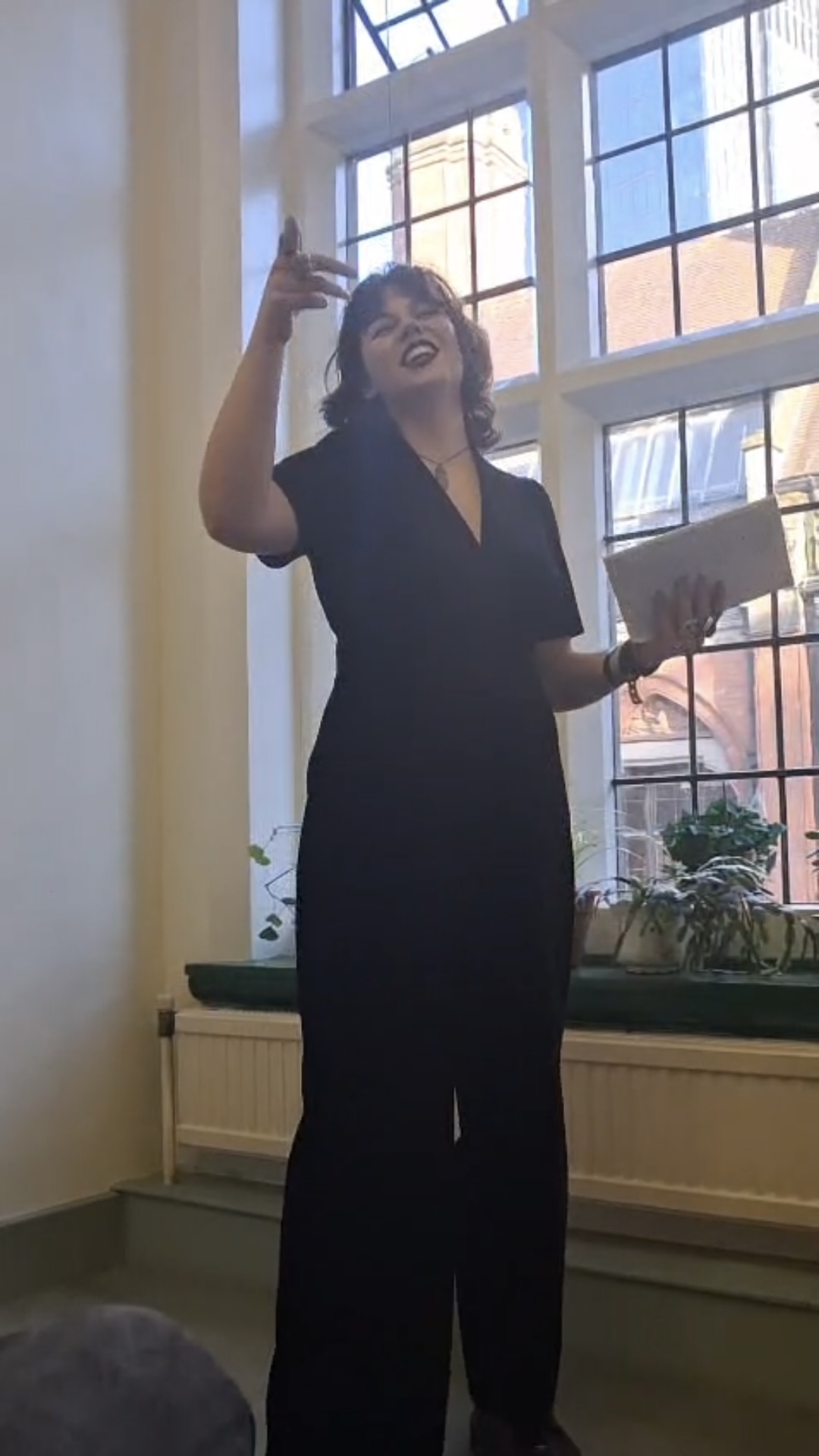 Person performing spoken word in front of large window.