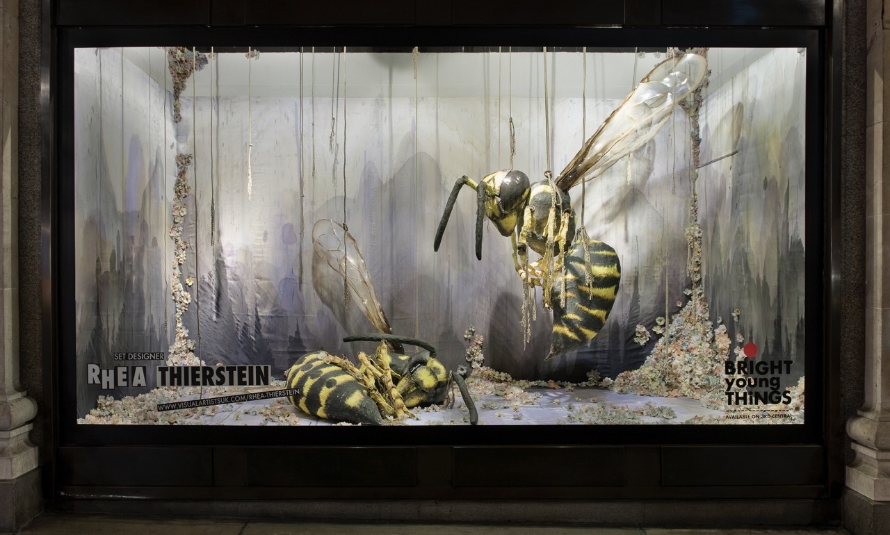 A shopfront window with two large-scale model wasps.