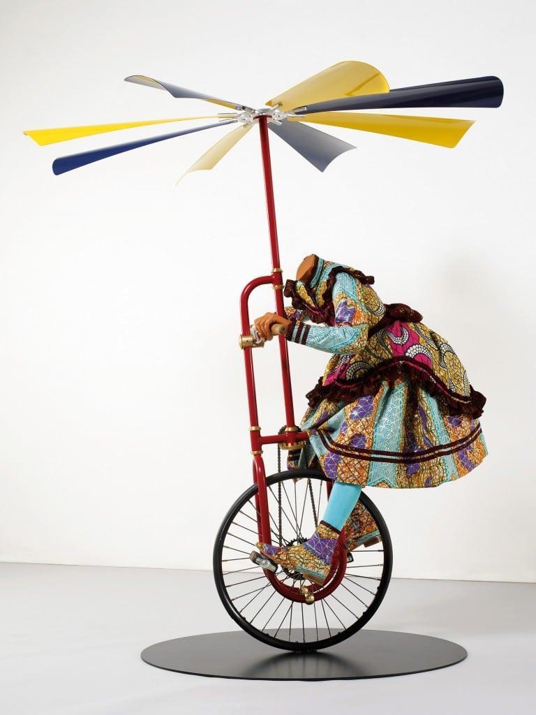 Model of a headless person riding a unicycle with a propeller at the top.