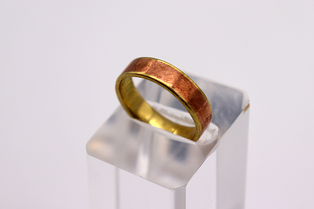 A copper-coloured ring lying on display.