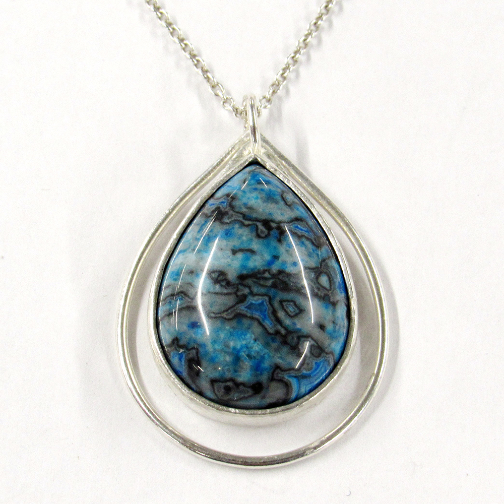 A silver pendant on a chain with a large blue and black gemstone in the centre.