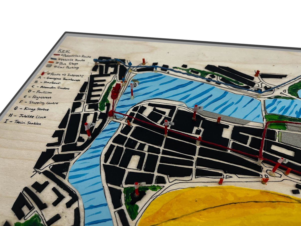Colourful plan of a site model with outlines of buildings, a river and beach.