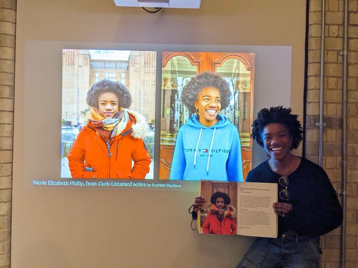 Nicole Elizabeth Phillip featured at the National Portrait Gallery stood in front of projections of her photoshoot.