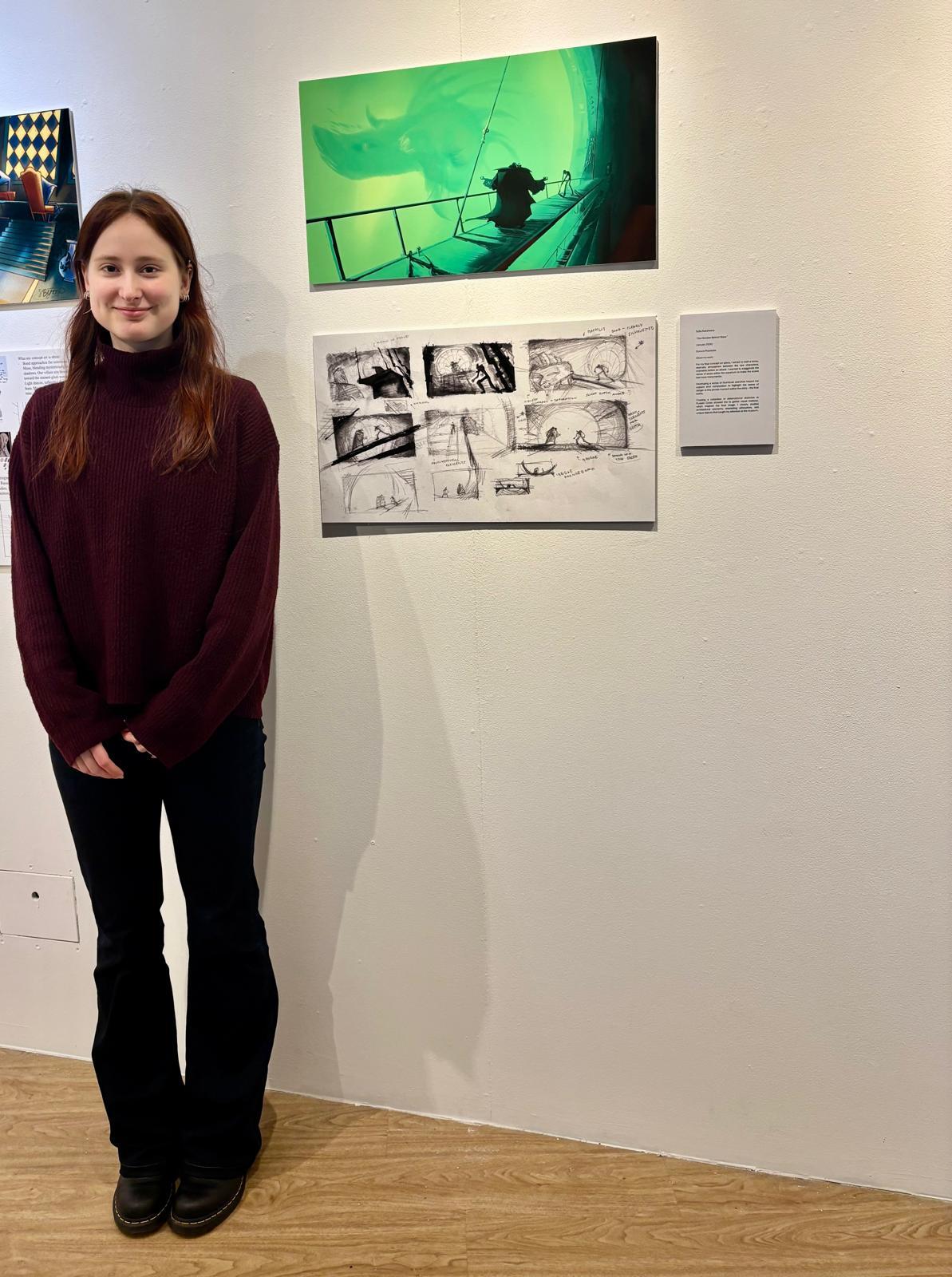 S Raksheeva standing next to two pieces of concept art displayed at Russell-Cotes Art Gallery & Museum, Bournemouth.