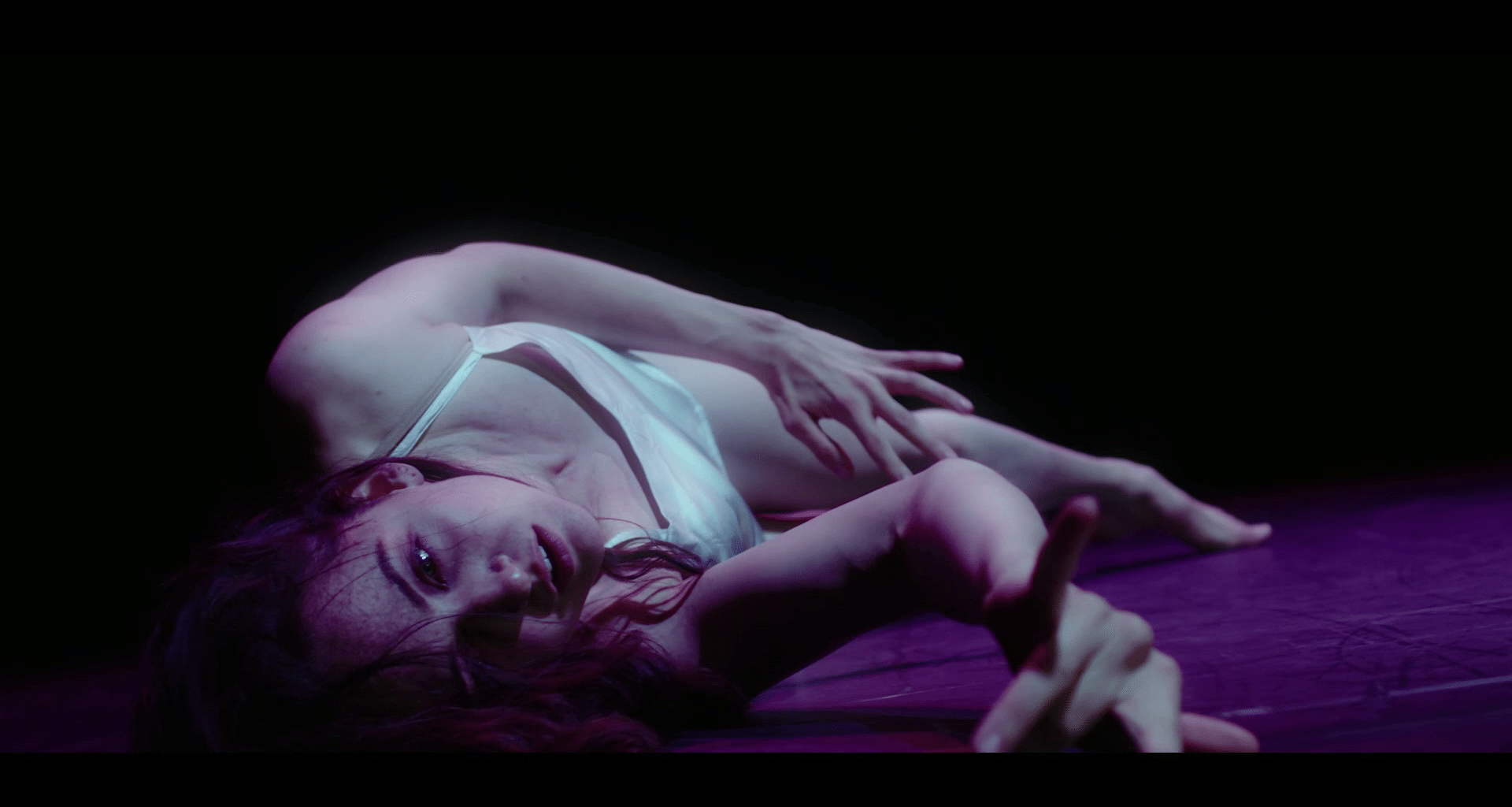 A person lying on a carpet with their right arm reaching out.