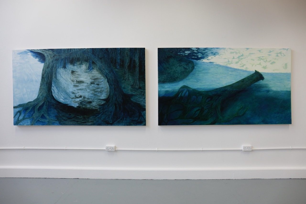 Two abstract paintings mounted on white wall. Left shows dark teal and blue curved forms. Right displays blue mountain-like shapes against lighter background.