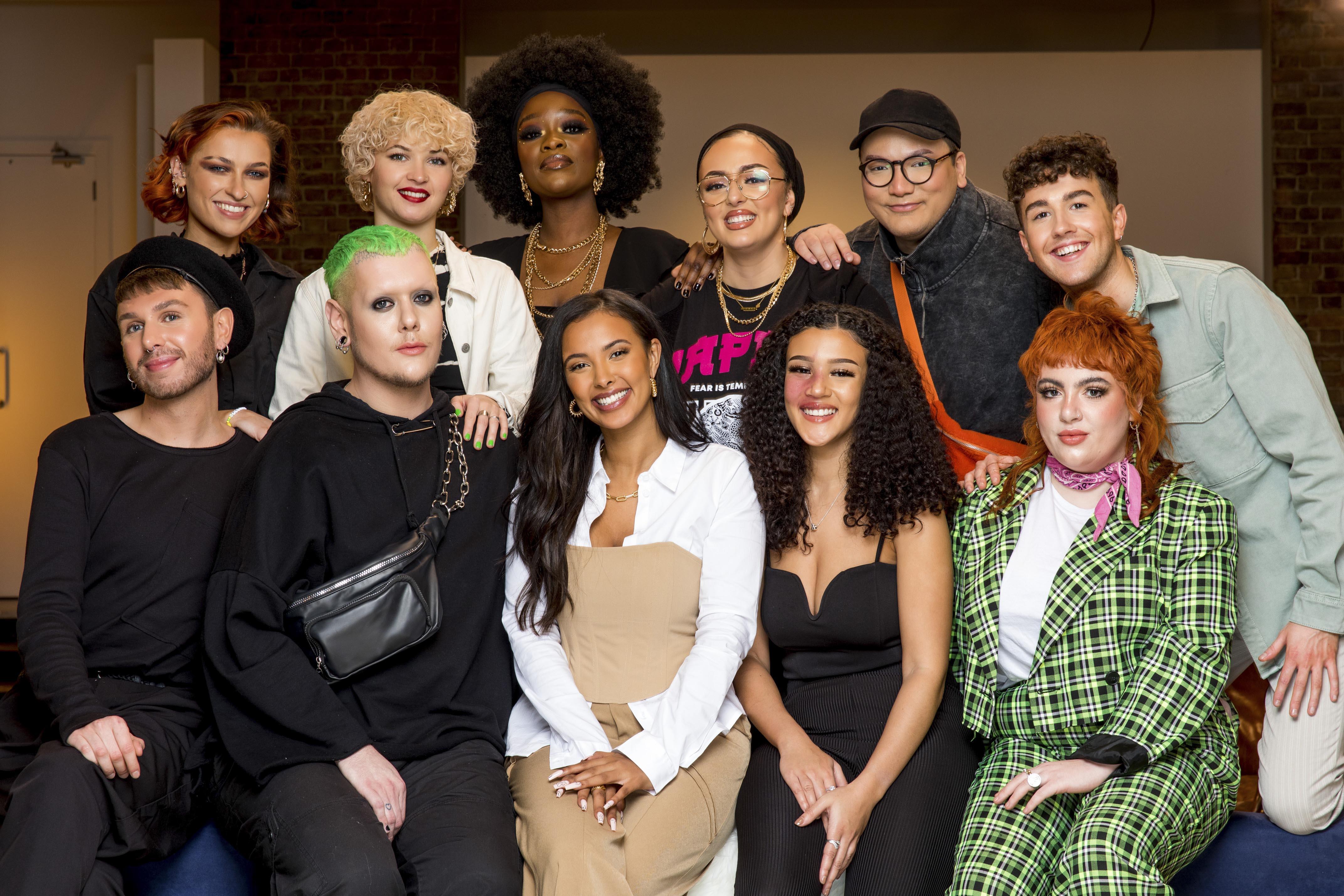 A group of 11 people in different outfits and make-up gather and pose for a photo.