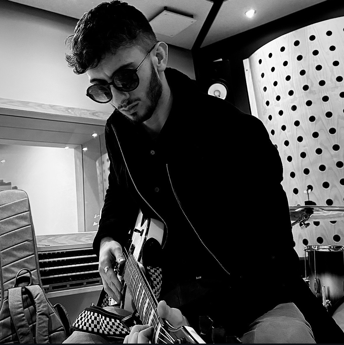Black and white image of E Horne (Spectator) playing a guitar in a recording studio.
