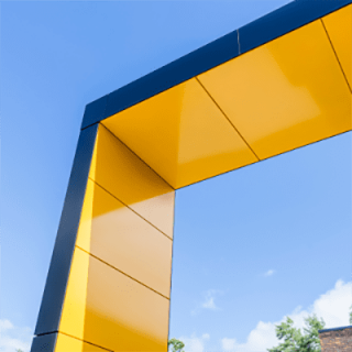 One corner of a high structure, viewed from below with a clear blue sky in the background.