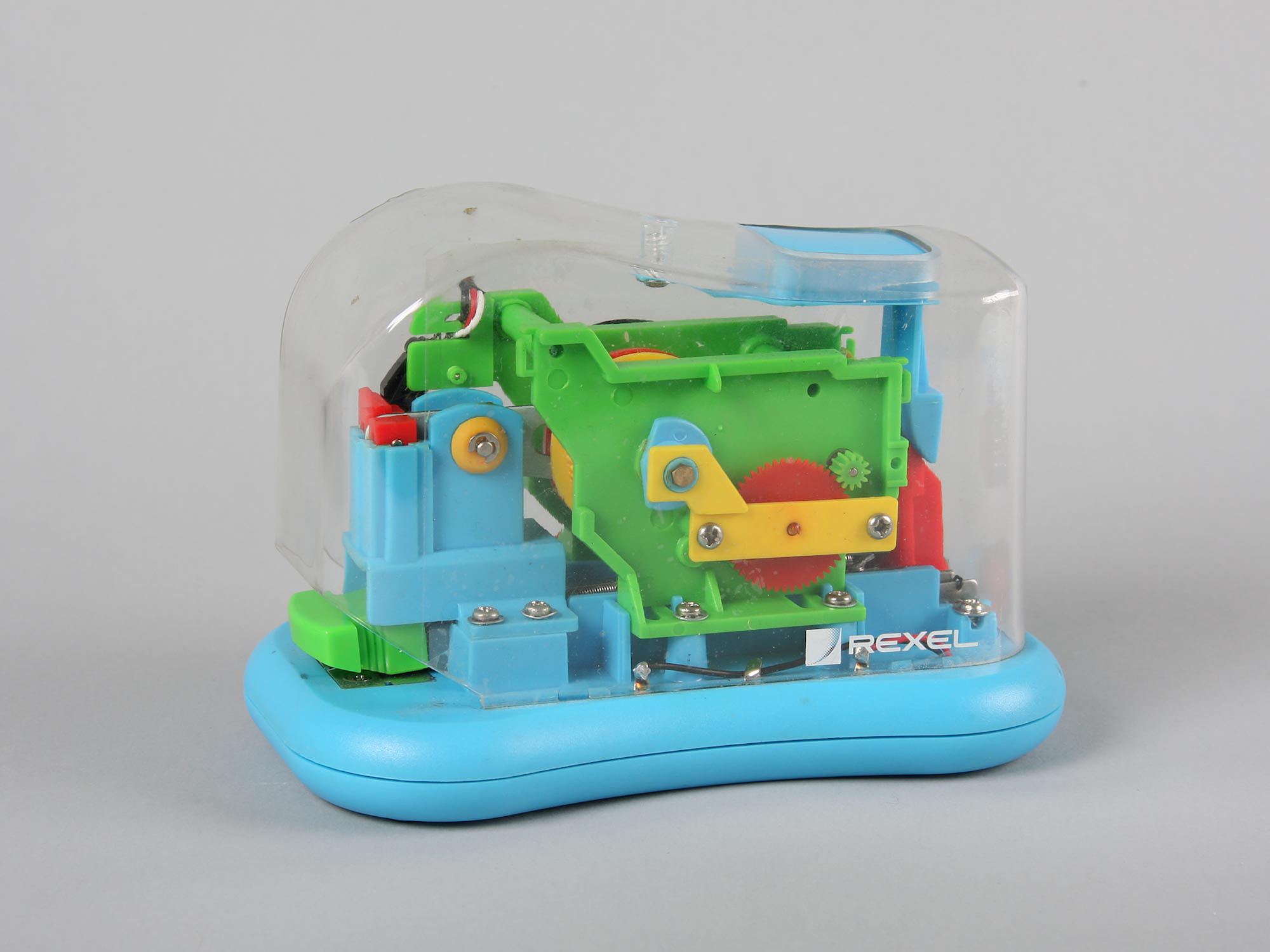 A colourful plastic stapler with a see-through body, showing the inner mechanisms.