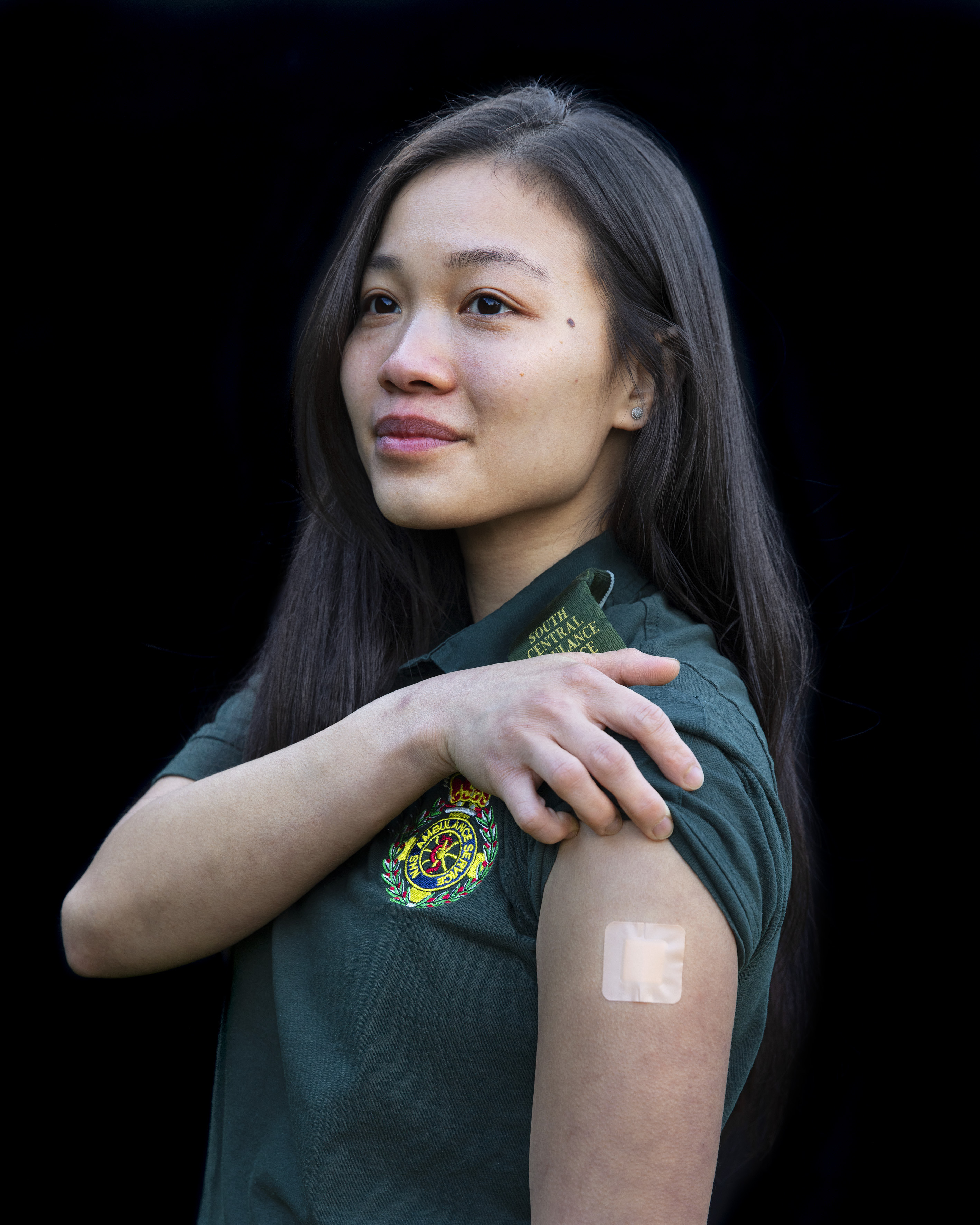 A person lifting their sleeve up and displaying a square plaster on their arm.