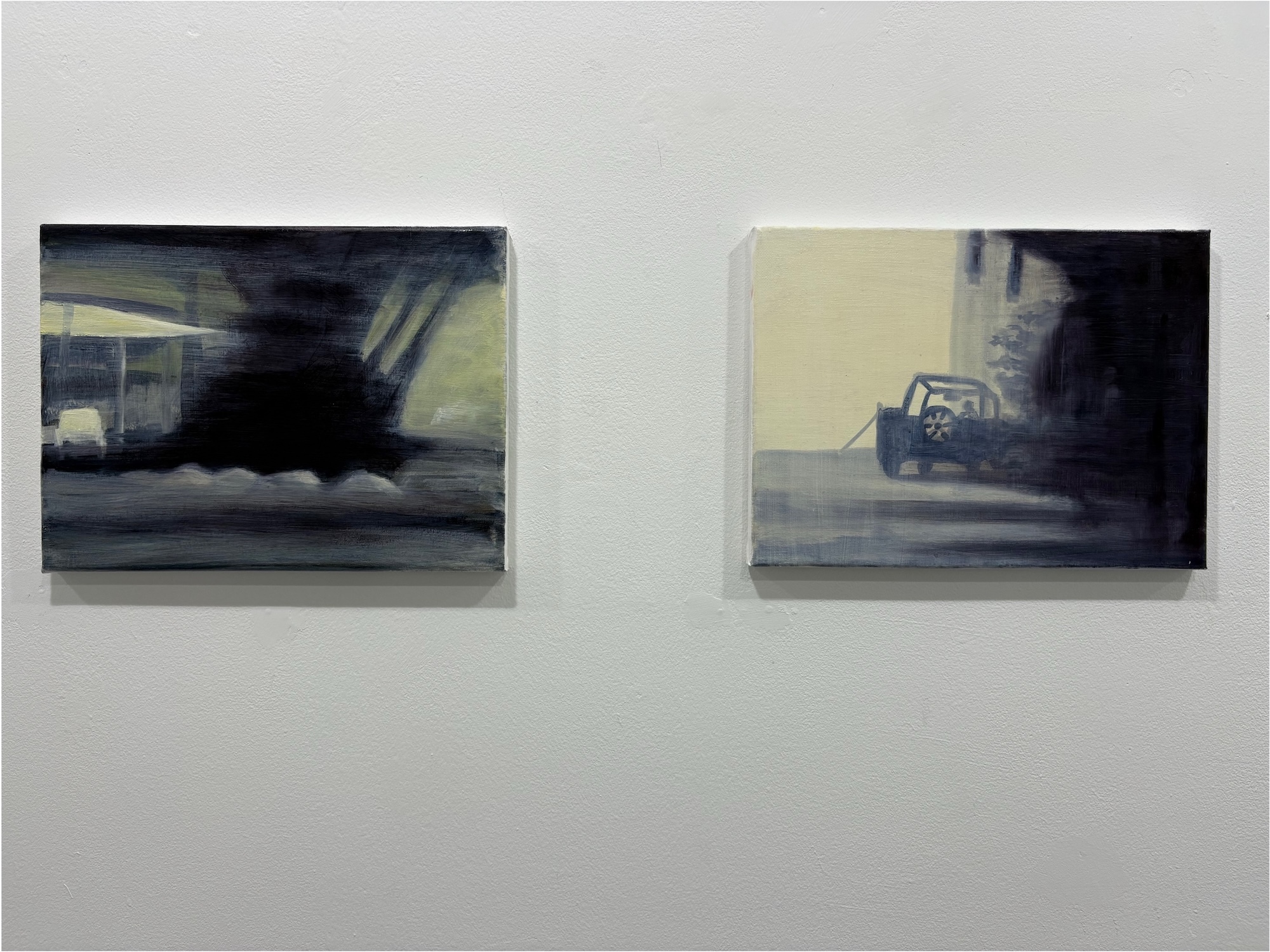 Two framed paintings on white wall. Left: dark greens and greys with horizontal brushstrokes. Right: pale yellow, dark blue and grey tones.