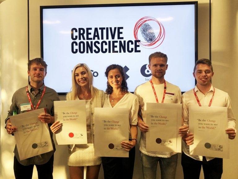 Five students stand in front of a screen with the words 'Creative Conscience' on it. All five are holding certificates.