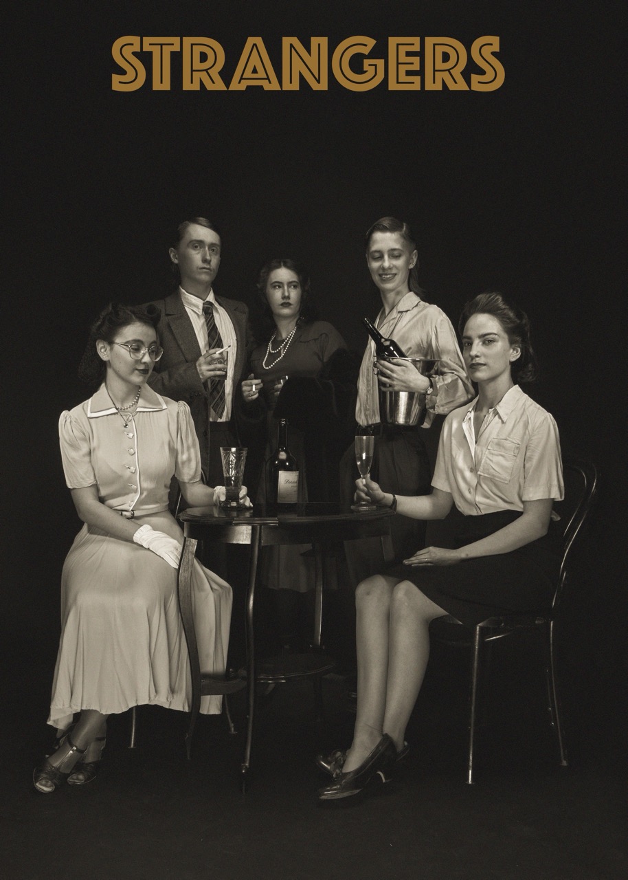 Five people dressed in vintage-style clothing sit and stand around a small table with glasses, beneath the word “STRANGERS” on a dark background.