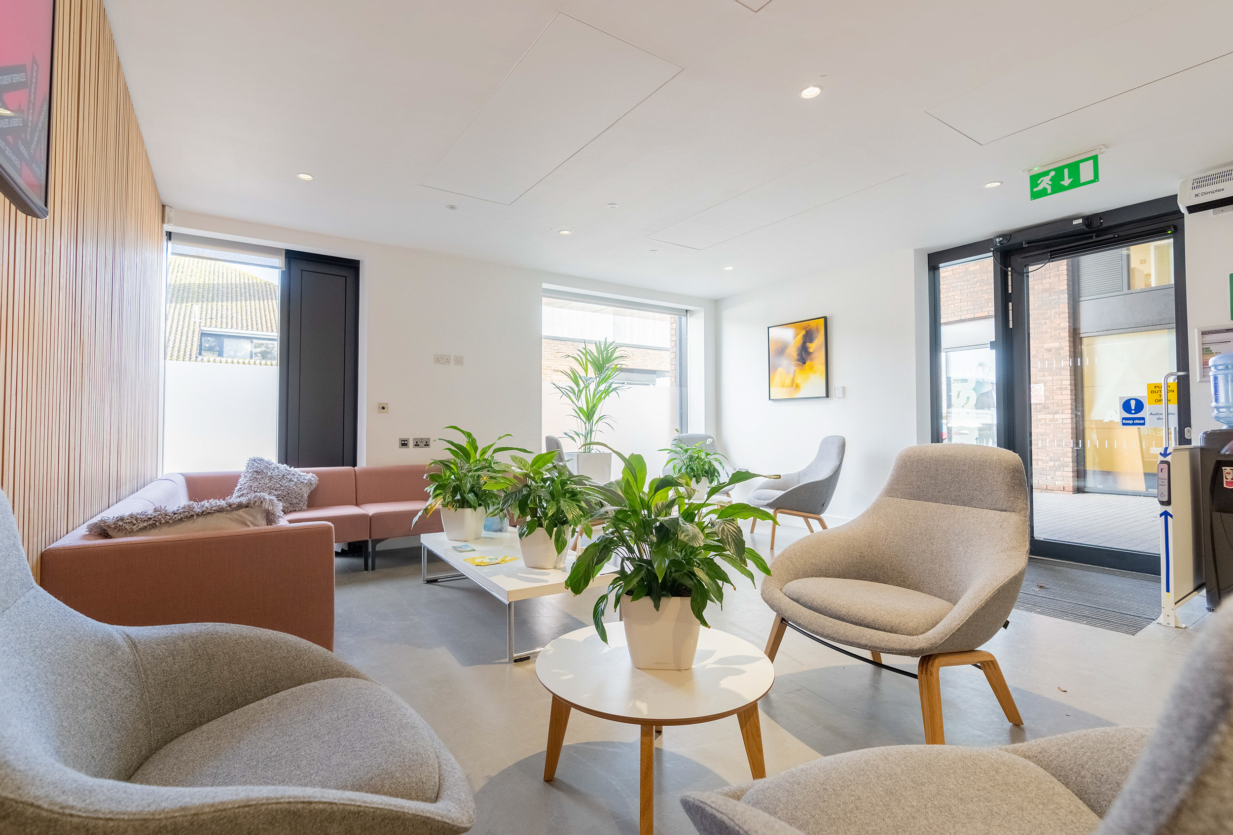 The refurbished Student Services' greeting area, including comfortable chairs and sofas, green pot plants and a tv screen with information on it – the area looks welcoming and inviting
