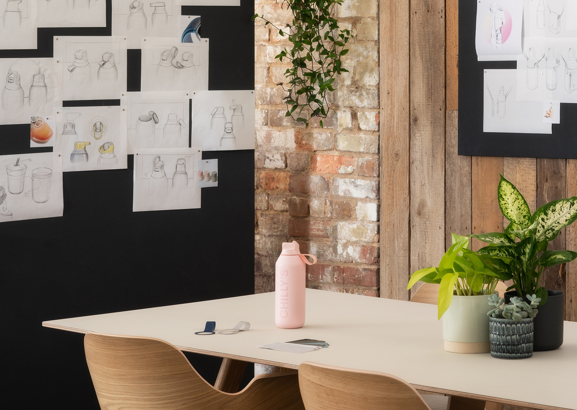 A water bottle sits on a table in front of design images