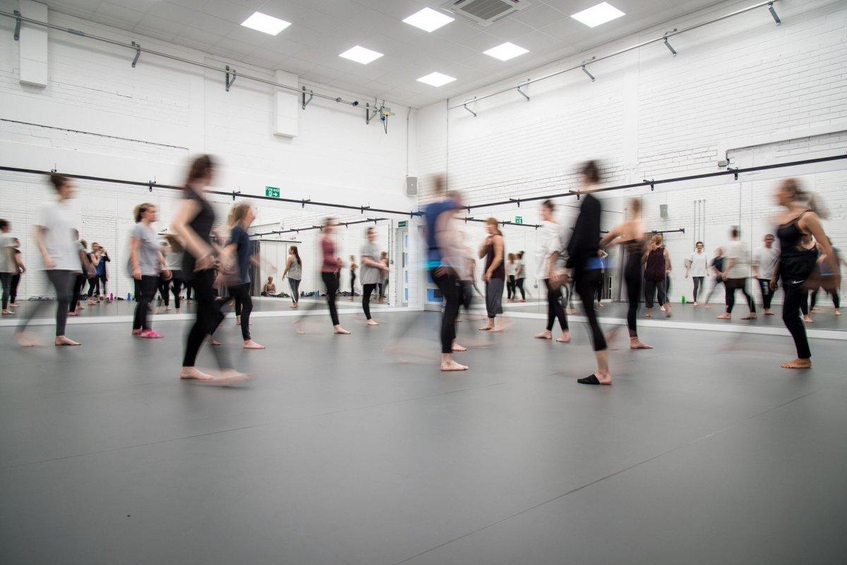 A group of dance students gathering in a dance studio.