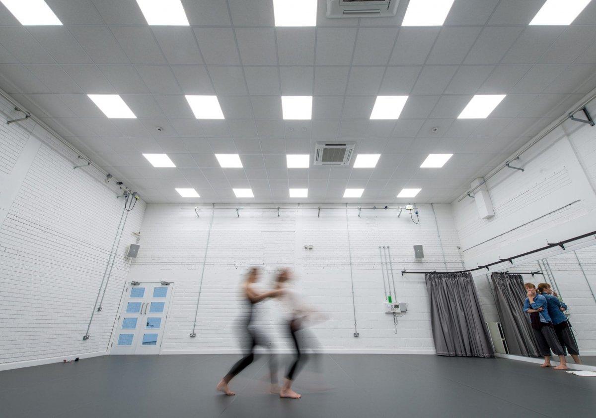 A pair of students dancing in AUB's dance studio. Another person stands watching from the right-hand side.