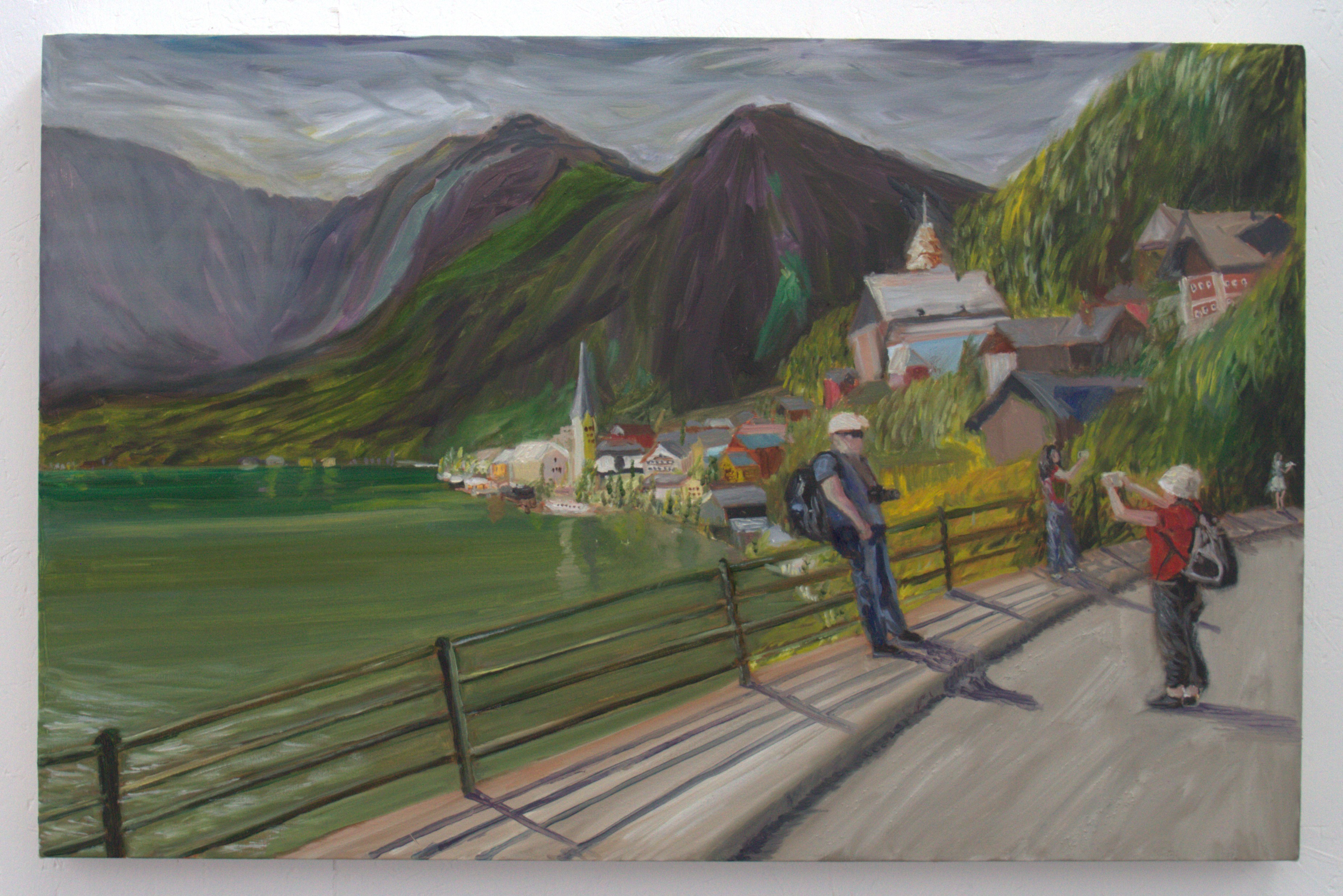 A landscape painting depicting a lake surrounded by mountains. In the foreground, two figures stand along a path, with one taking a photo of the scenery. Colourful houses are visible on a hillside, and lush greenery lines the water's edge.