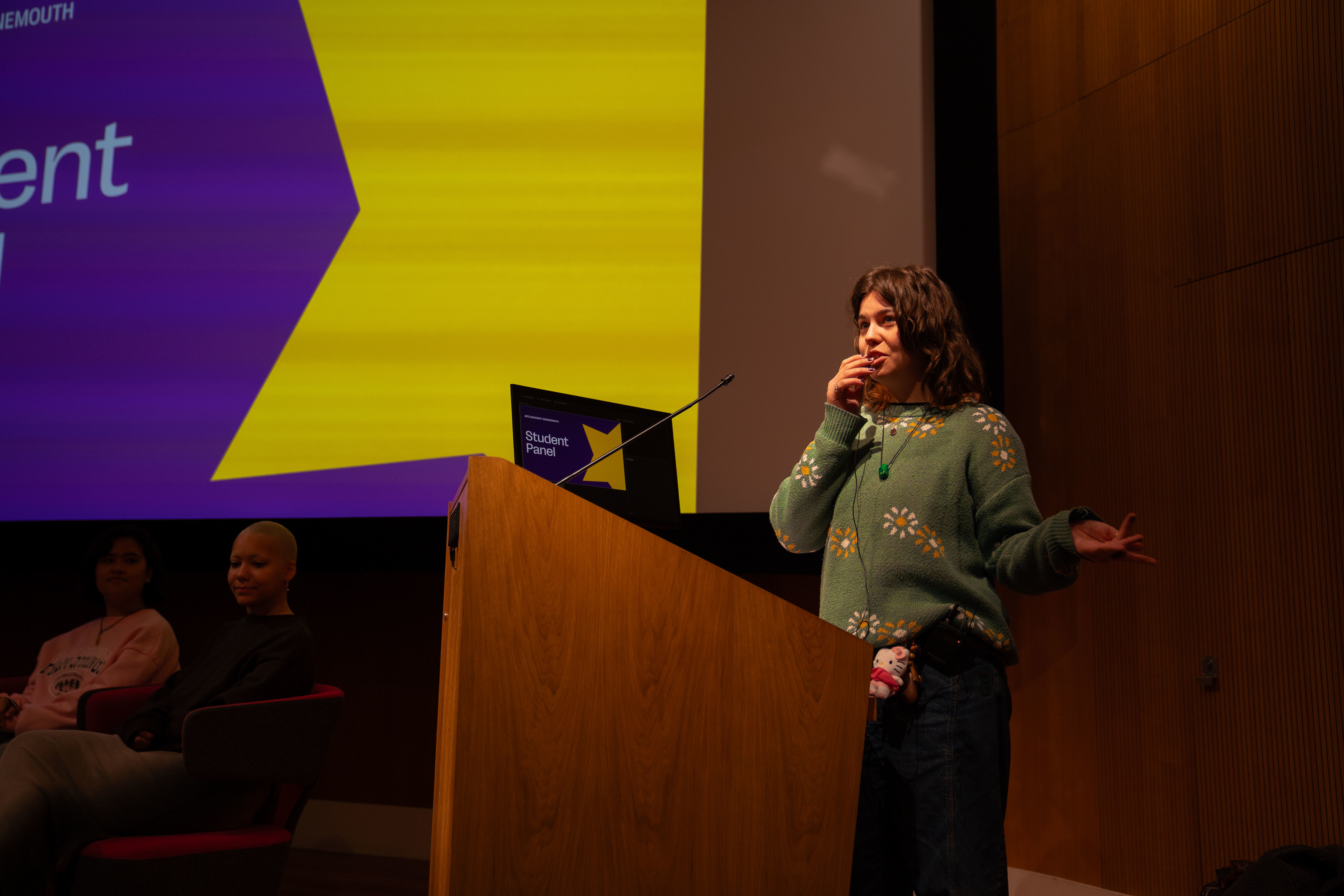 An AUB student standing at a lectern in a lecture theatre presenting a student panel.