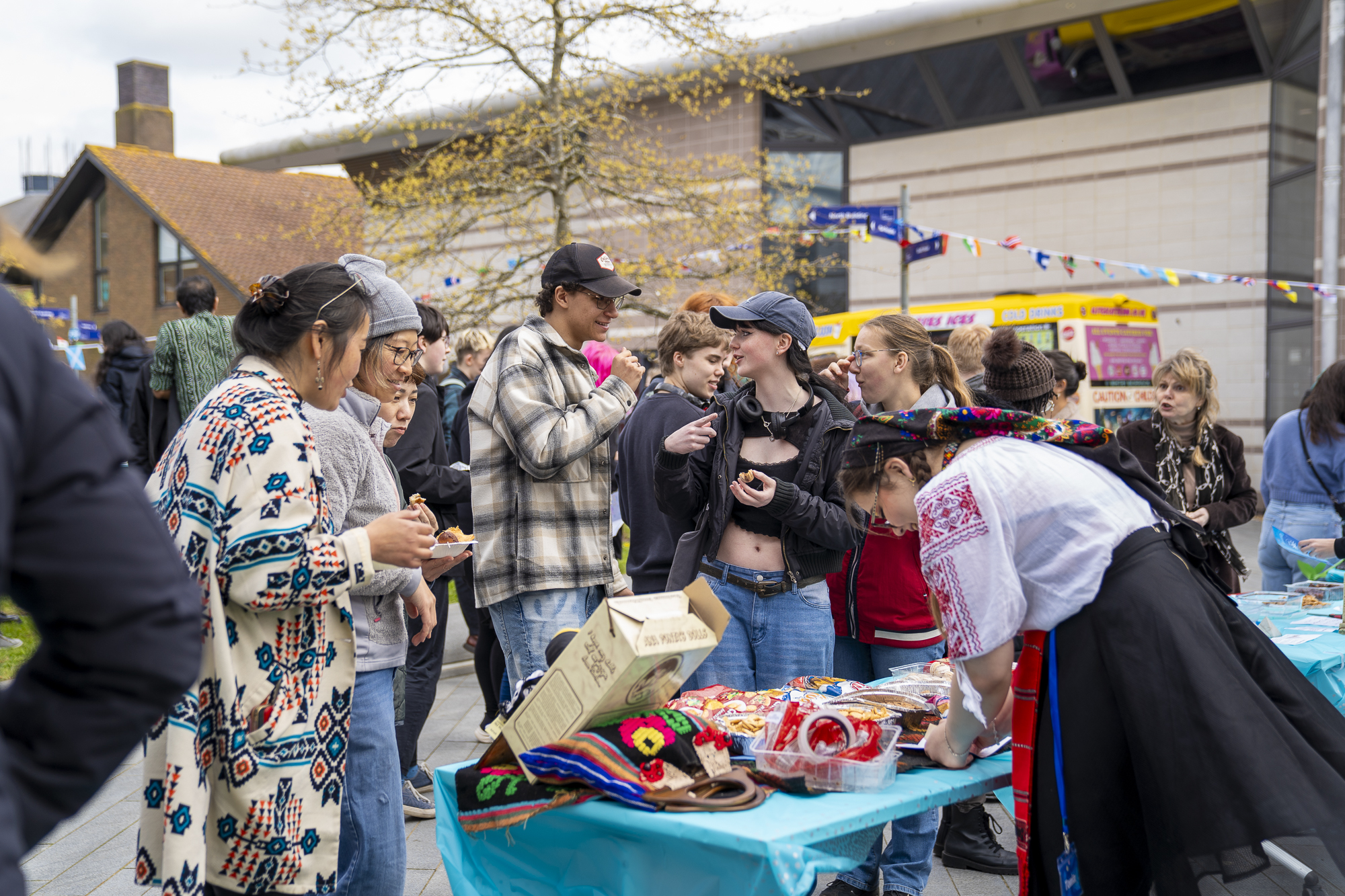 Students gathered on campus around a colourful stall, talking to one another.