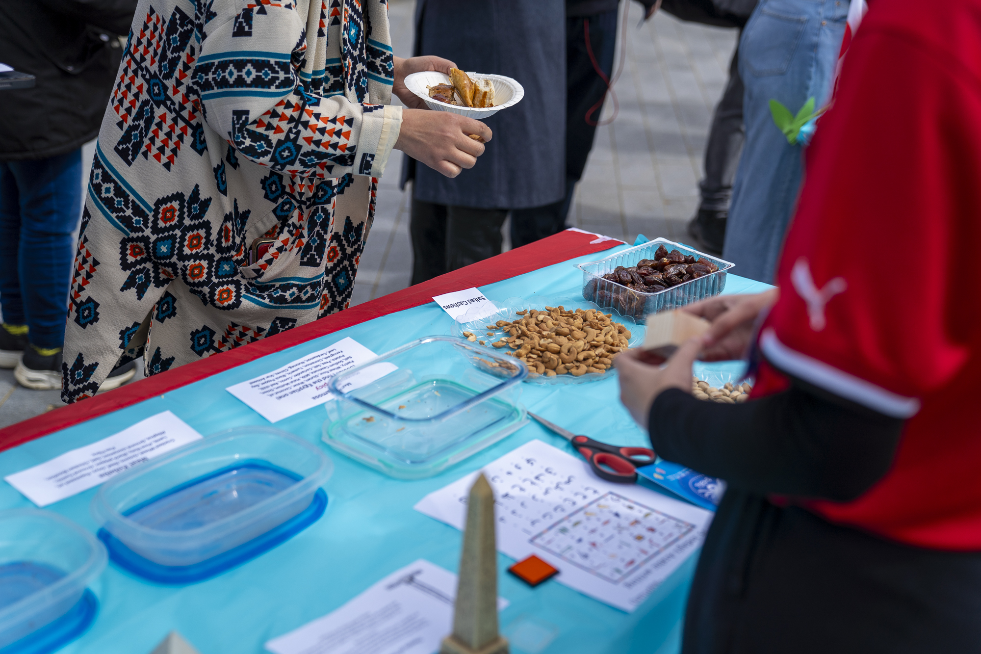 Bright blue table with snacks, student's hands and blurred person in front.