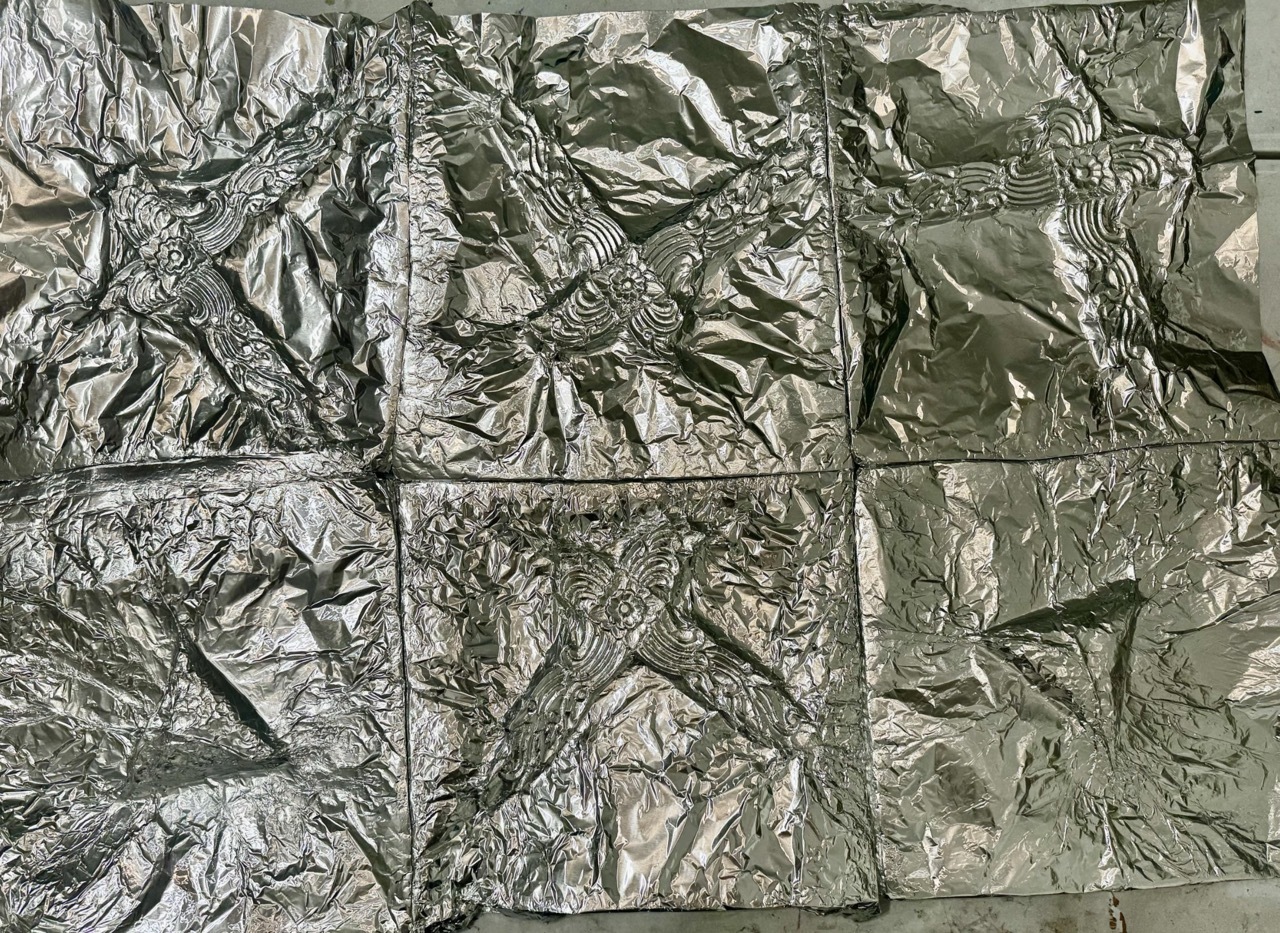 Nine squares of crumpled silver foil arranged in a 3x3 grid, each with different wrinkled textures and reflective surfaces
