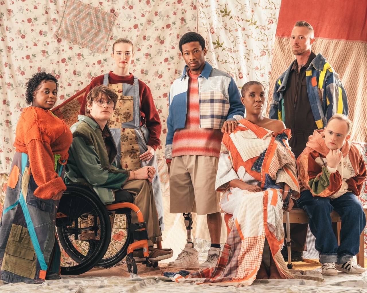 Seven disabled individuals, each with different conditions, modelling colourful handmade sustainable patchwork garments.