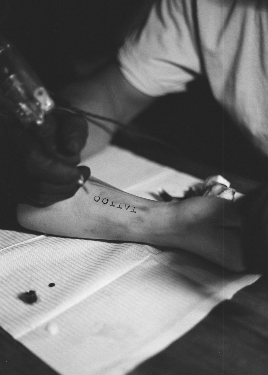 Black and white image of a person's arm with a tattoo of the word 'tattoo'.