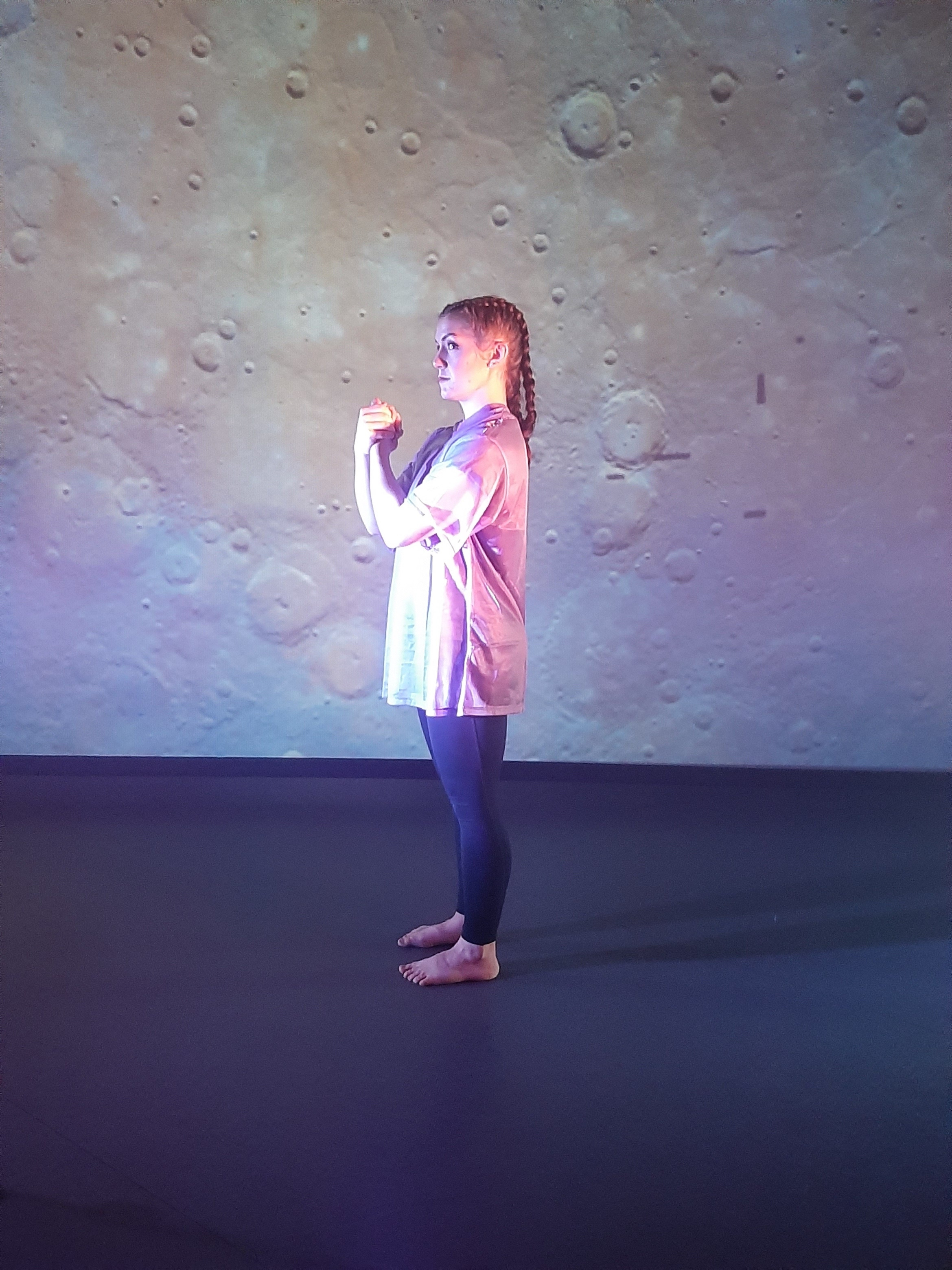 BA (Hons) dance student performing a dance in front of a backdrop based on the planet Mercury.