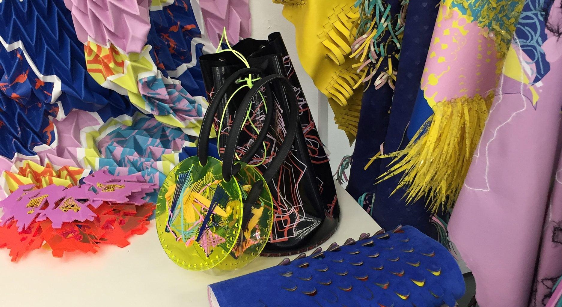 A small bag resting on a table surrounded by pieces and rolls of fabric.