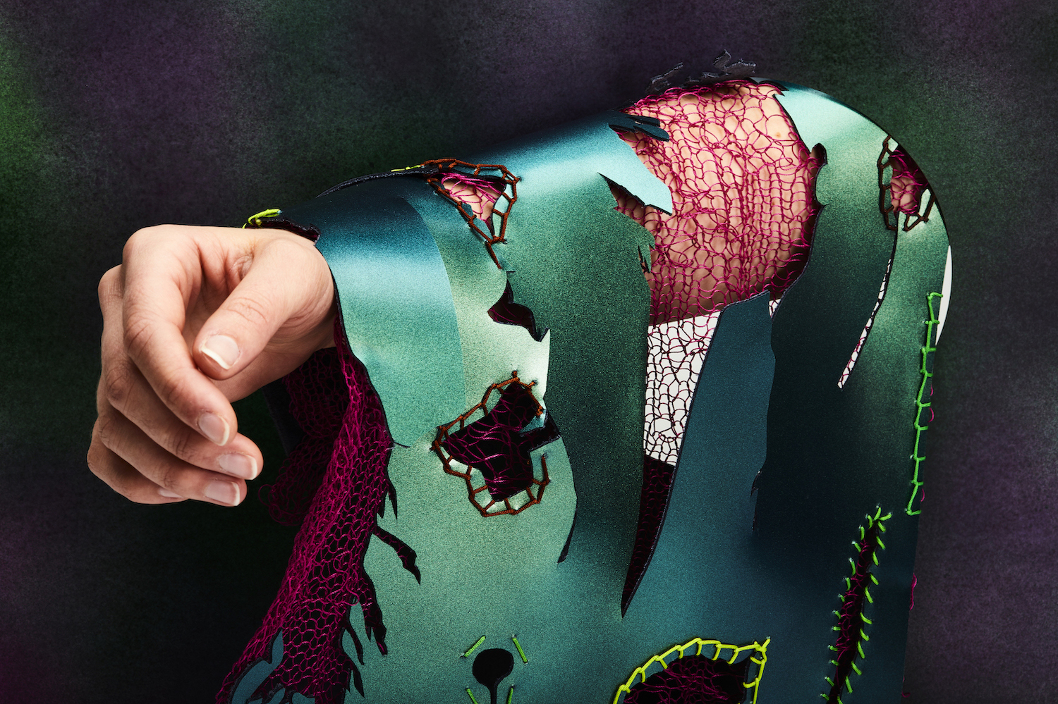Red and green patterned textile patterns and textures, layered over a model's arm in the sunlight.