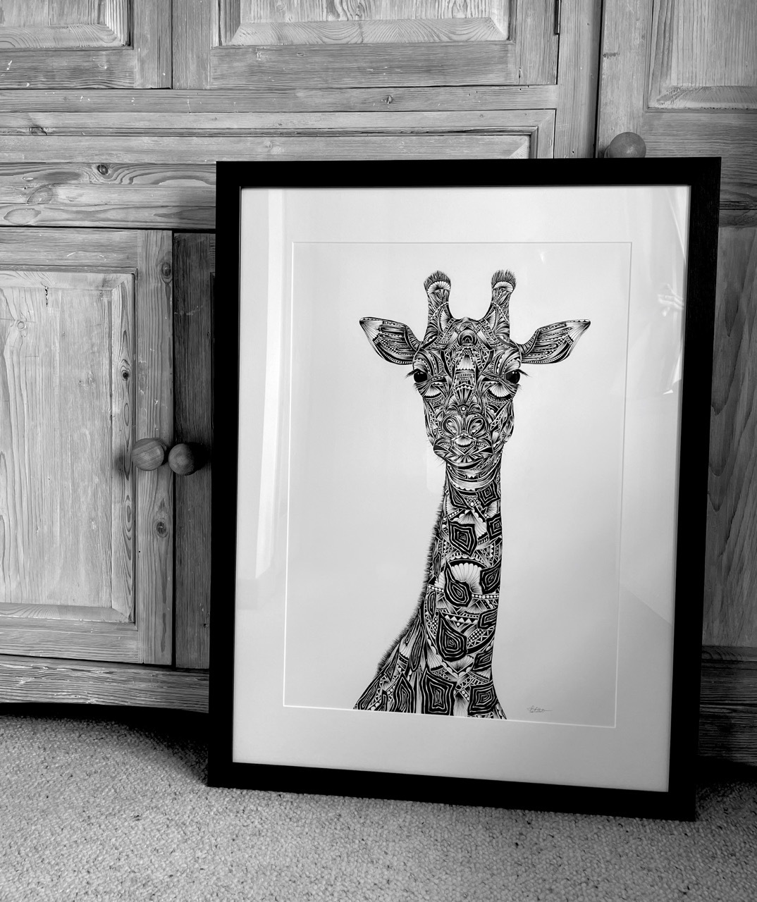 Framed, intricate patterned drawing of a giraffe, pen on paper, black and white shot.
