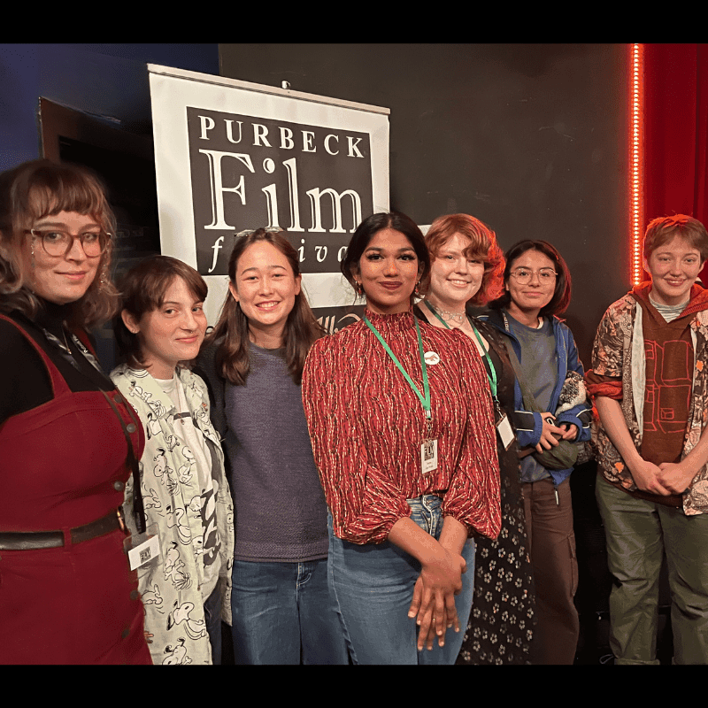 Student winners of 'The Man Who Loved Flowers', stood in front of a Purbeck Film Festival banner.