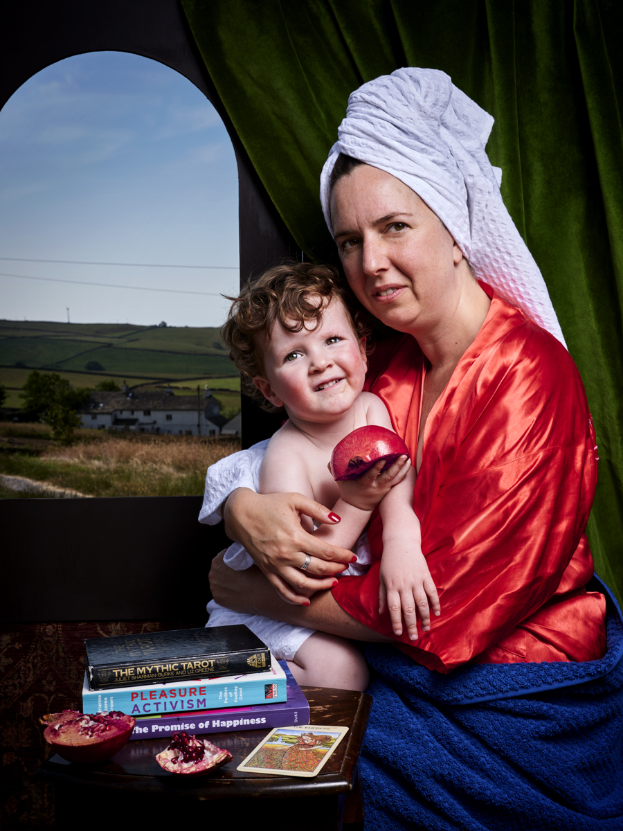 Painting of a woman wearing a dressing gown and turban holding a child, sitting next to a small stack of books in front of an arched window