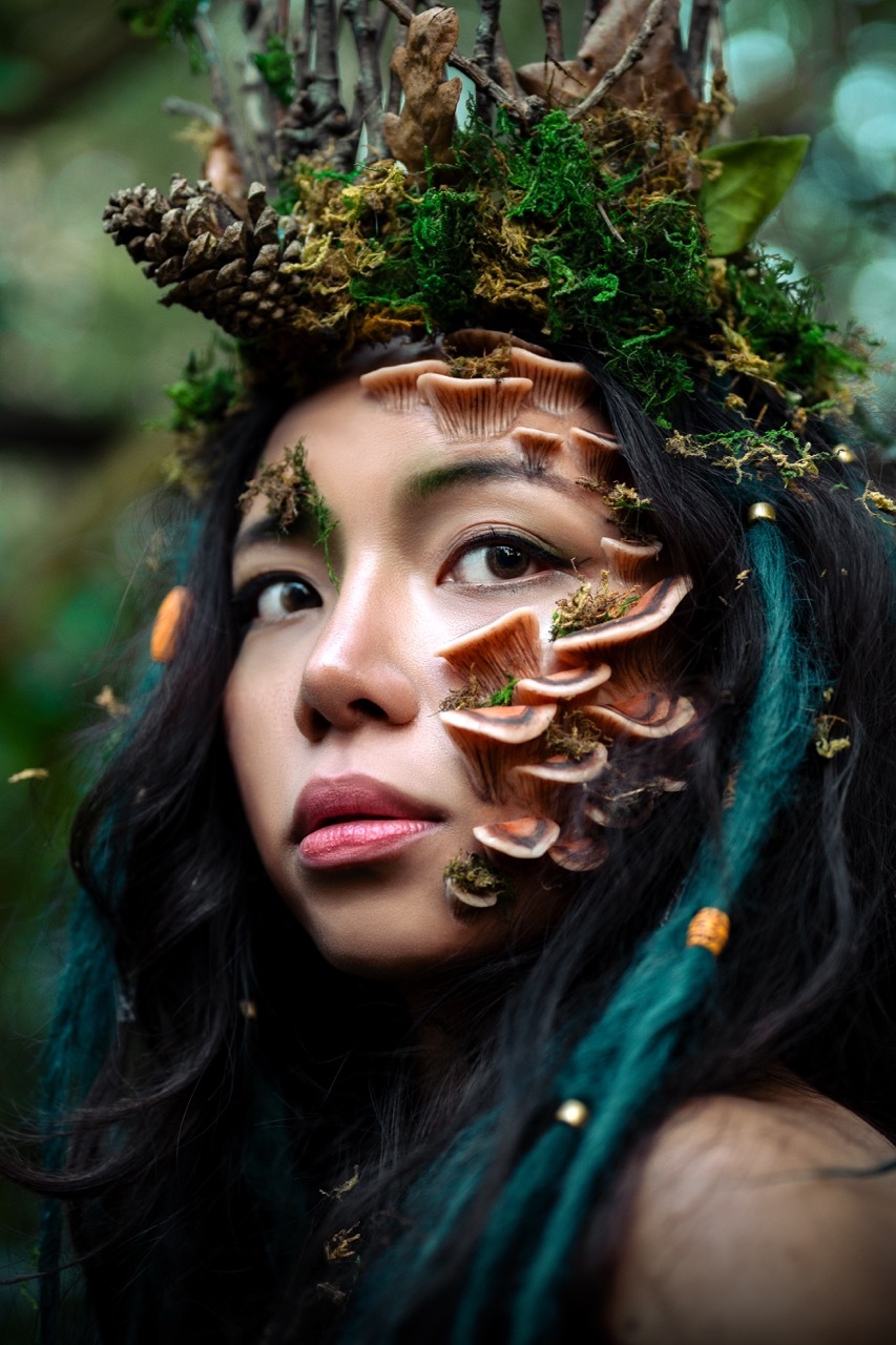 Editorial shot of a model wearing detailed, fungal prosthetics in a forest, green and mossy.